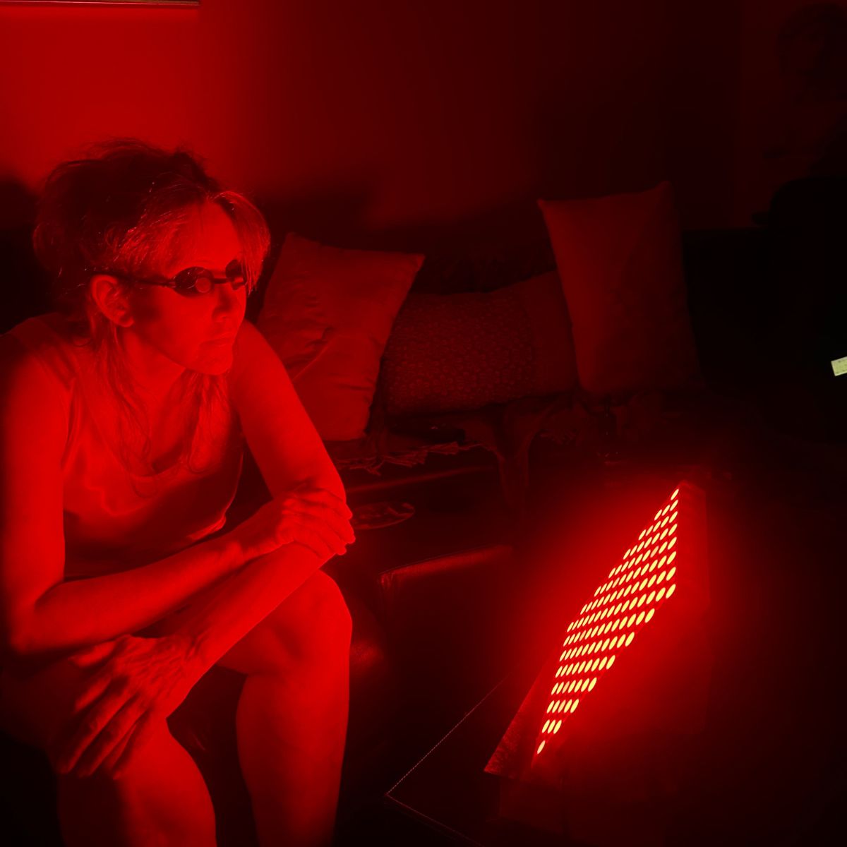 Woman Using Red Light Therapy Panel with Goggles on