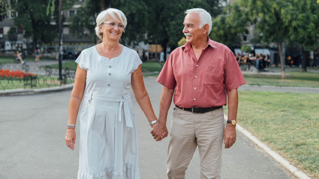 2 older adults together holding hands and looking at eachother