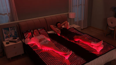 man and woman laying on bed with red light therapy bed