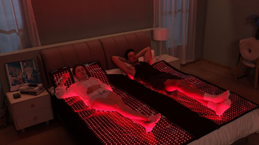 man and woman laying on bed with red light therapy bed