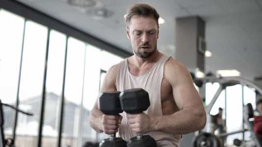 man holding 2 dumbells while looking at the floor