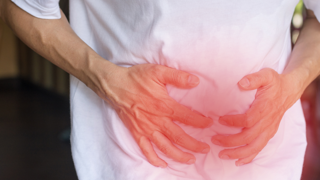 man holding onto stomach with red emitting off hands
