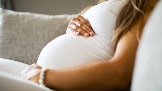 pregnant woman laying on couch while holding belly
