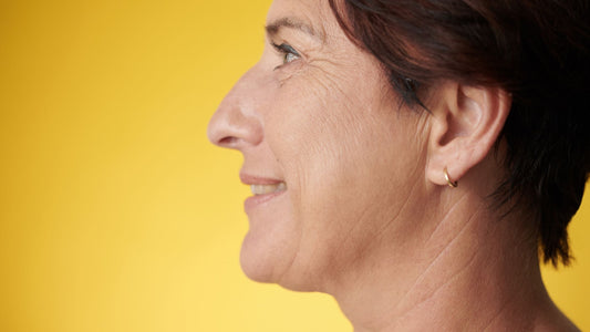 side profile of older woman smiling with a yellow background