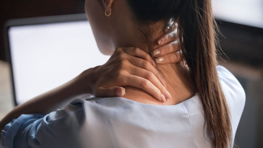 woman holding back of neck while looking into screen