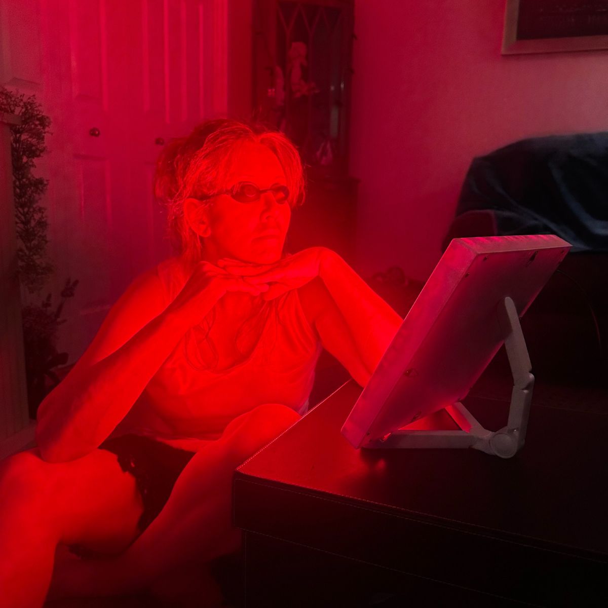 Woman Using Red Light Therapy Panel with Goggles on