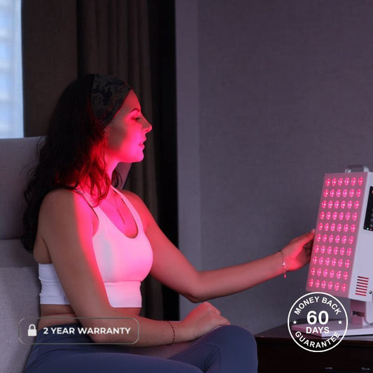 Woman holding red light therapy panel while it emits onto her face
