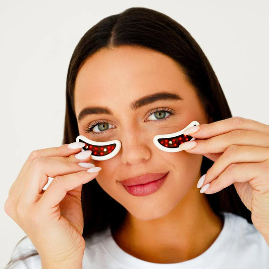 Woman holding up red light therapy pads under eye
