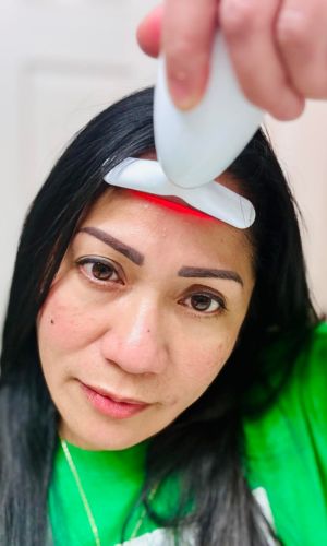 Woman_using_face_sculpting_tool_on_forehead_with_red_light