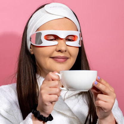 lady_drinking_coffee_with_under_eye_red_light_therapy_device_on