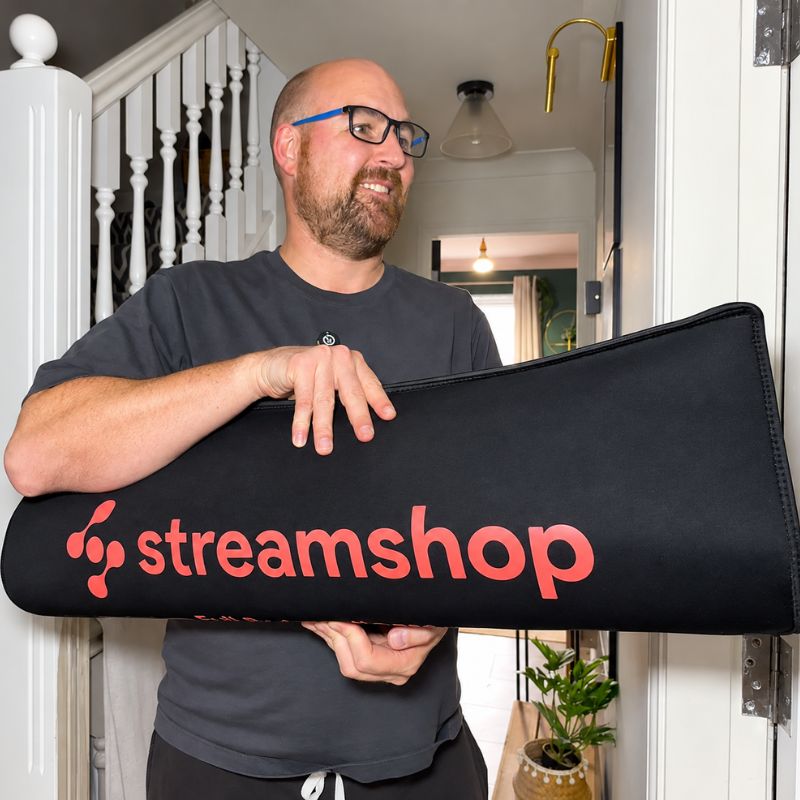 man_holding_red_light_therapy_mat_rolled_up_at_home