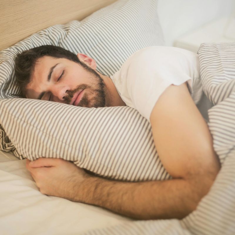man sleeping in bed after red light therapy mat use