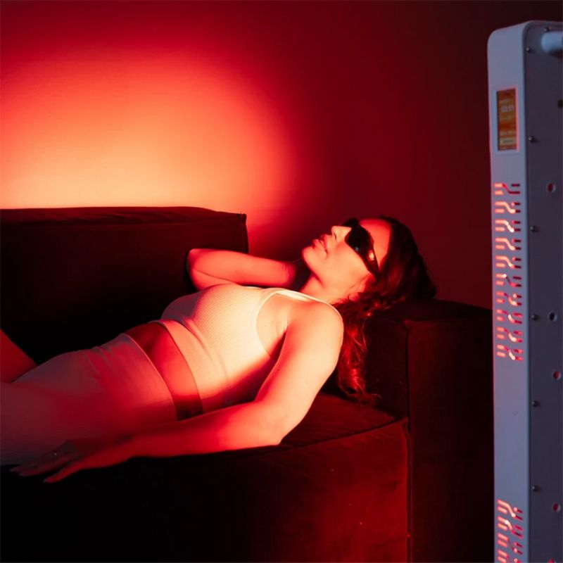 medicalgraderedlighttherapypanelss300withwomanlayinginfrontofit
