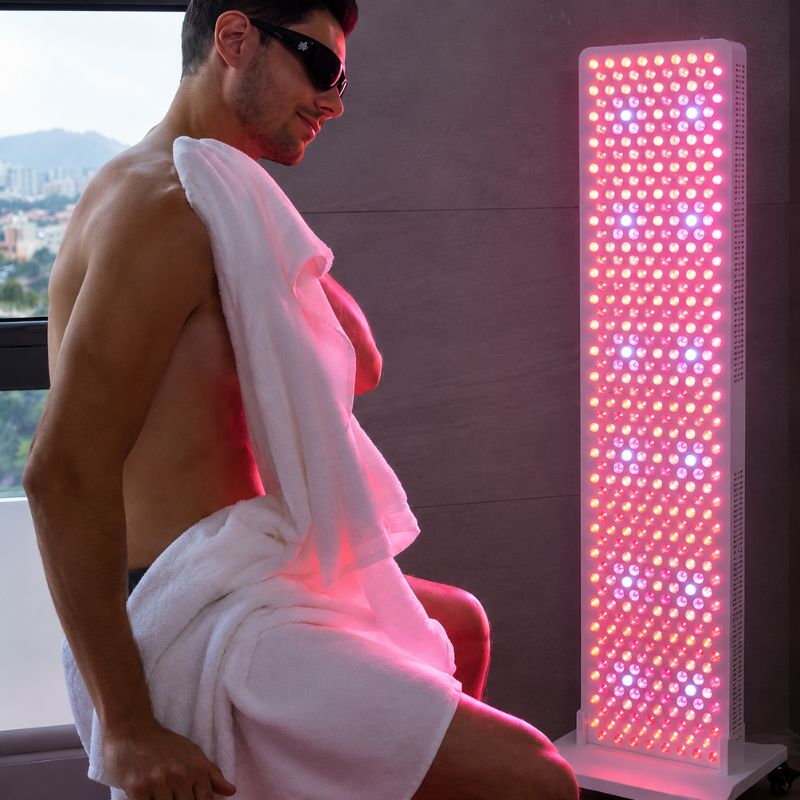 medicalgraderedlighttherapypanelss450promansittinginfrontofpanelwithglasseson
