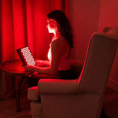 sr60redlighttherapypanelwithwomanholdingitwhilesittinginchair