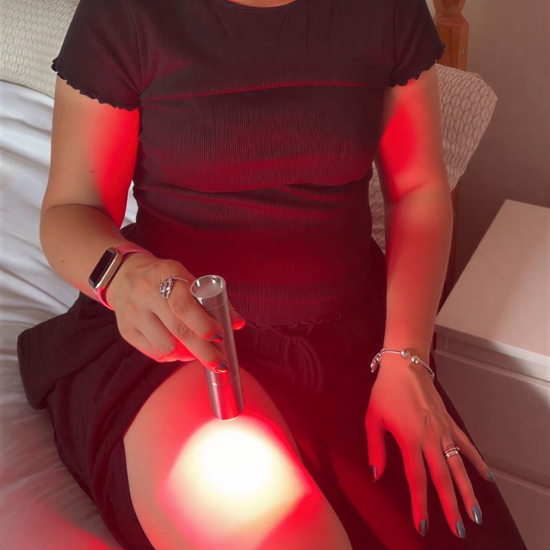 woman_holding_red_light_therapy_torch_and_using_on_her_thigh