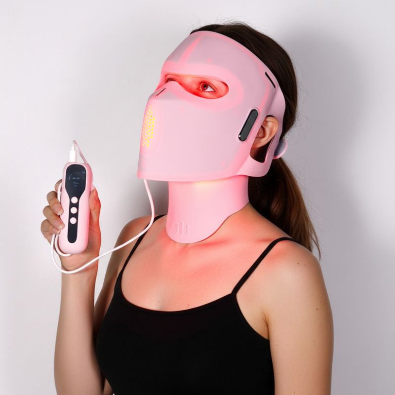 woman_wearing_pink_face_mask_and_neck_piece_while_holding_controller_up