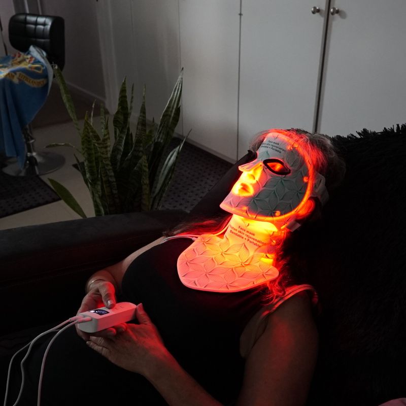 womanholdingcontrollerwithledlighttherapymaskonface