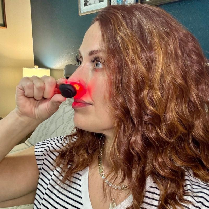 womanholdingredlighttherapyfornasalcongestioninsidehernose