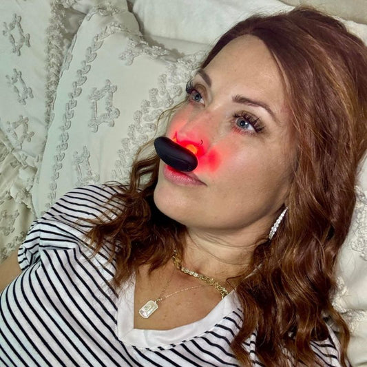 womanlayingdownwithredlighttherapyfornasalcongestiondeviceinhernose